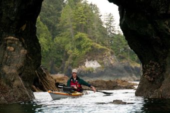 image by Bruce Kirkby West Coast Expeditions owner Dave Pinel paddling under a sea arch
